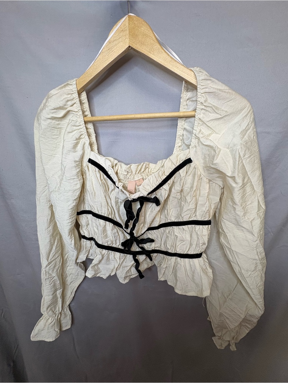 Cream top with black ribbon details in a ruffle bottom